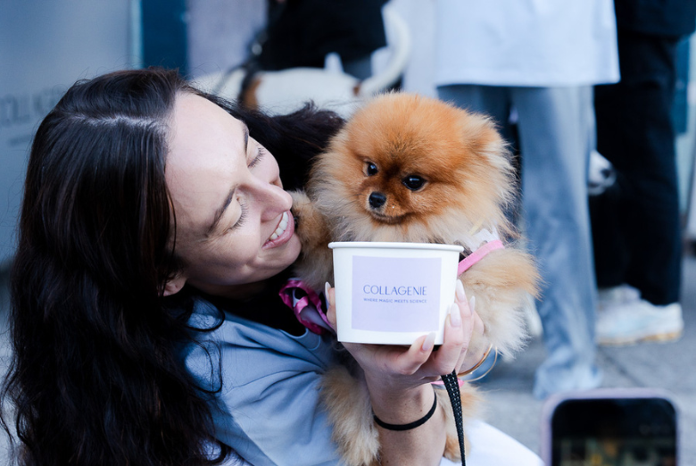 Woman holding a small fluffy Pomeranian near a cup labeled 'COLLAGENIE' showing off a pet-friendly product moment.